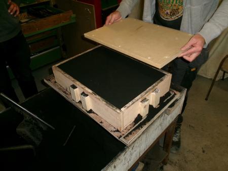 putting a board on top of the bottom half of the mold