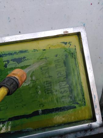 water hose washing away ink on used silkscreen